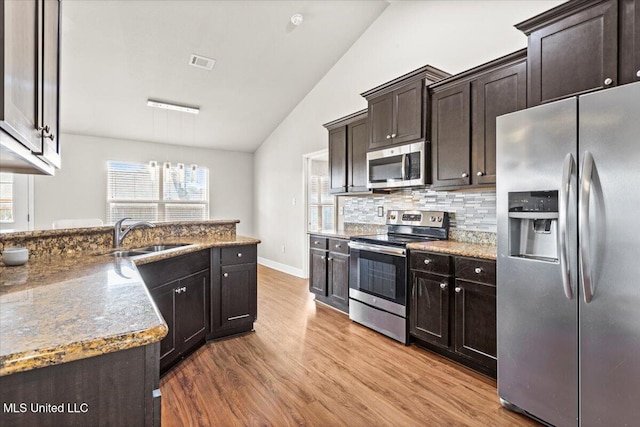 kitchen featuring sink, tasteful backsplash, vaulted ceiling, appliances with stainless steel finishes, and pendant lighting