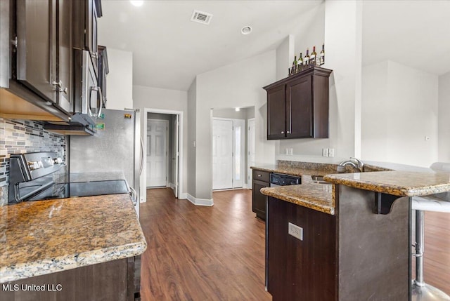 kitchen featuring sink, dark hardwood / wood-style flooring, a kitchen bar, stove, and light stone countertops