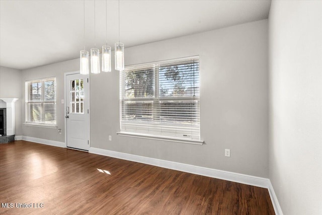 unfurnished dining area with hardwood / wood-style floors and a high end fireplace