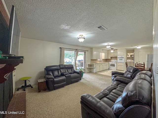 living room featuring sink, light colored carpet, a textured ceiling, and ceiling fan