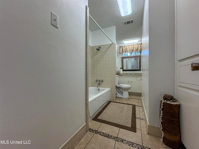 bathroom featuring tiled shower / bath, a textured ceiling, toilet, and tile patterned flooring