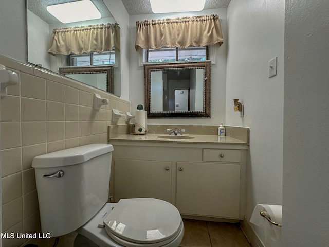 bathroom featuring vanity, toilet, tile patterned floors, and tile walls