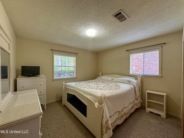 bedroom featuring a textured ceiling, multiple windows, and carpet floors