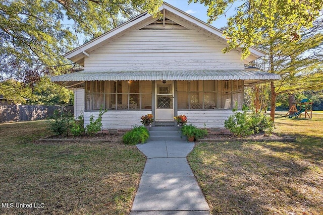 view of front of property with a front yard, covered porch, and a playground