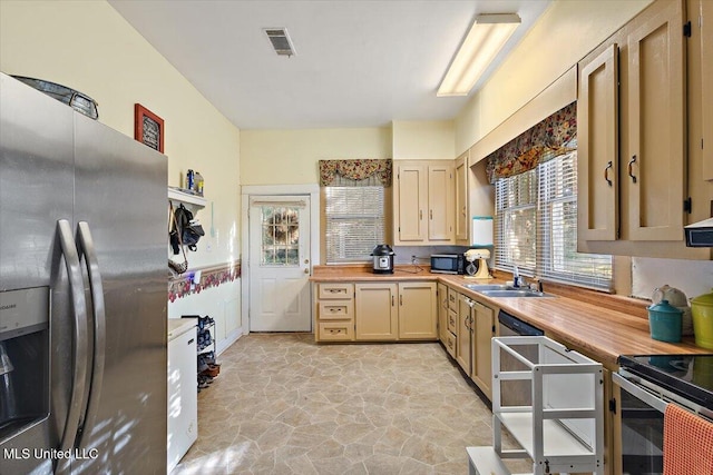 kitchen with appliances with stainless steel finishes, sink, light brown cabinetry, and butcher block countertops