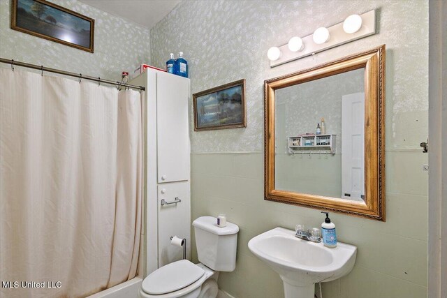 bathroom with toilet, curtained shower, sink, and tile walls