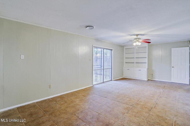 empty room featuring wooden walls, crown molding, built in features, and ceiling fan