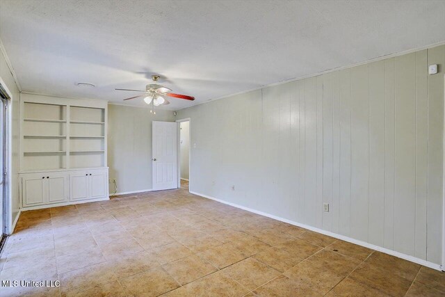 338 Lake Of Pines Dr, Jackson, MS 39206 - unfurnished room featuring a ceiling fan, a textured ceiling, wood walls, built in features, and baseboards