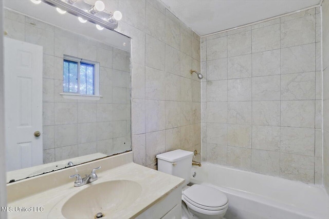 full bathroom featuring tiled shower / bath, vanity, toilet, and tile walls