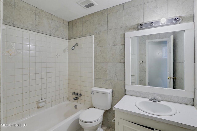 full bathroom with tile walls, vanity, tiled shower / bath combo, and toilet