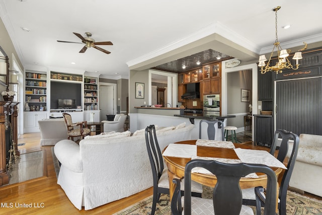 dining room with light hardwood / wood-style floors, ornamental molding, ceiling fan with notable chandelier, and built in features