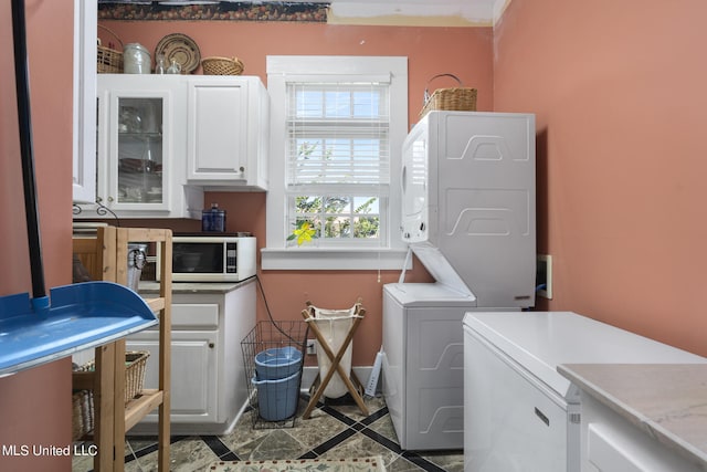 clothes washing area with cabinets and stacked washer and dryer