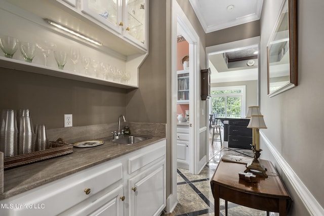 bar with sink, white cabinets, and crown molding