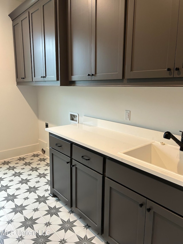 clothes washing area with hookup for an electric dryer, washer hookup, cabinets, and sink