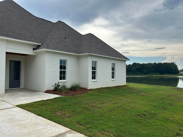 view of side of property featuring a water view and a lawn