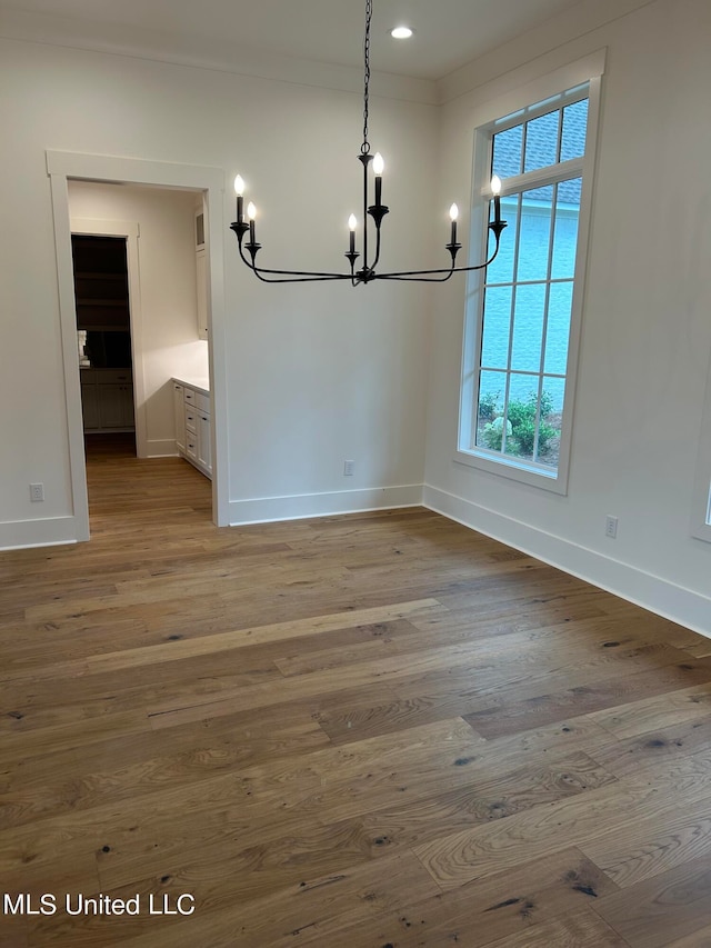 unfurnished dining area with crown molding, hardwood / wood-style flooring, and a chandelier