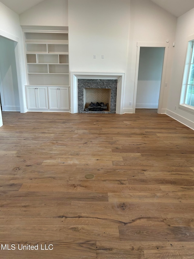 unfurnished living room featuring hardwood / wood-style flooring, lofted ceiling, and a fireplace