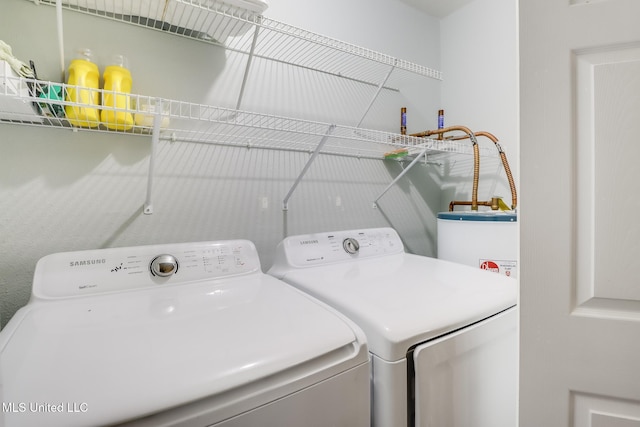 clothes washing area featuring washing machine and dryer, laundry area, and water heater