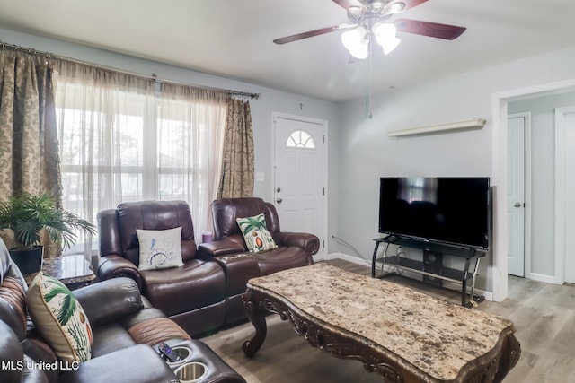 living area with baseboards, light wood-style flooring, and a ceiling fan