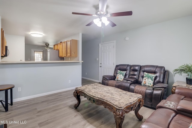 living room featuring light wood-style flooring, a ceiling fan, and baseboards