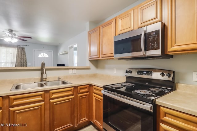 kitchen with stainless steel appliances, light countertops, a ceiling fan, and a sink