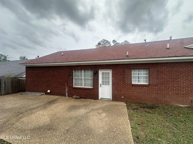 713 Hawthorn Green Dr, Ridgeland, MS 39157 - back of house with fence, brick siding, a chimney, and roof with shingles