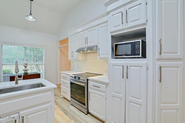 kitchen with light hardwood / wood-style floors, white cabinetry, sink, appliances with stainless steel finishes, and decorative light fixtures