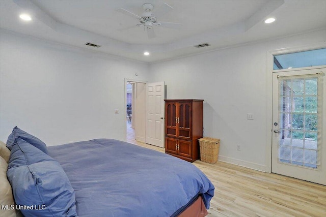 bedroom featuring light hardwood / wood-style floors, ceiling fan, and a tray ceiling