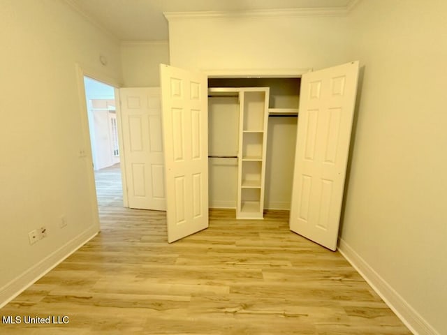 unfurnished bedroom with ornamental molding, a closet, and light hardwood / wood-style floors