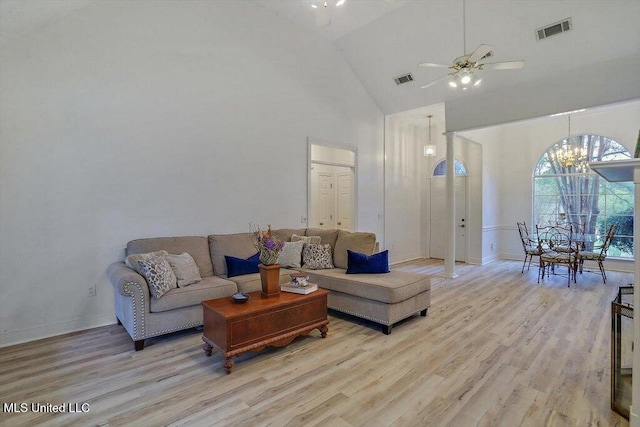 living room with high vaulted ceiling, ceiling fan with notable chandelier, and light hardwood / wood-style flooring