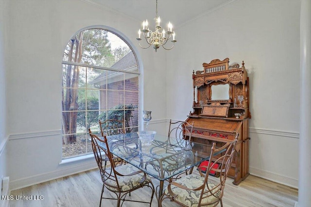 dining area with light wood-type flooring, crown molding, and a notable chandelier