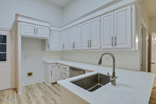 kitchen with light hardwood / wood-style floors, sink, light stone countertops, stainless steel dishwasher, and white cabinets