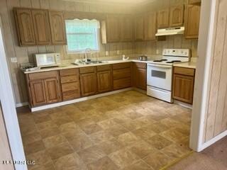 kitchen with light countertops, white appliances, brown cabinets, under cabinet range hood, and a sink