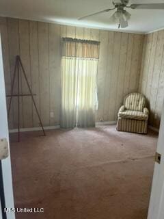 unfurnished bedroom with carpet flooring, wood walls, and ceiling fan