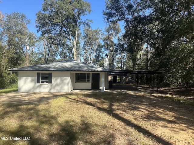 rear view of house featuring a carport and a lawn