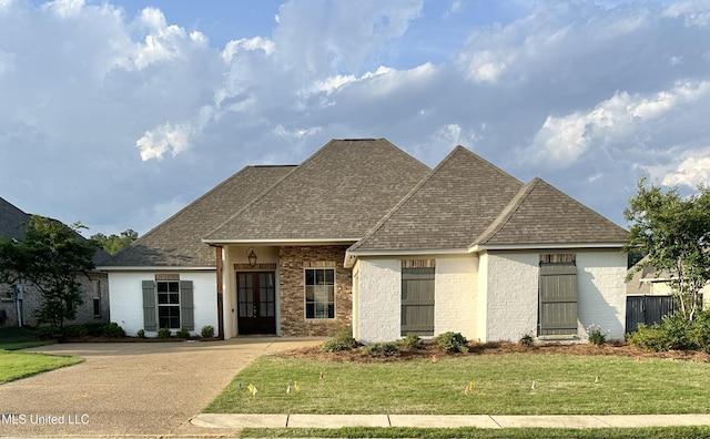 view of front of house with brick siding, a front yard, and roof with shingles