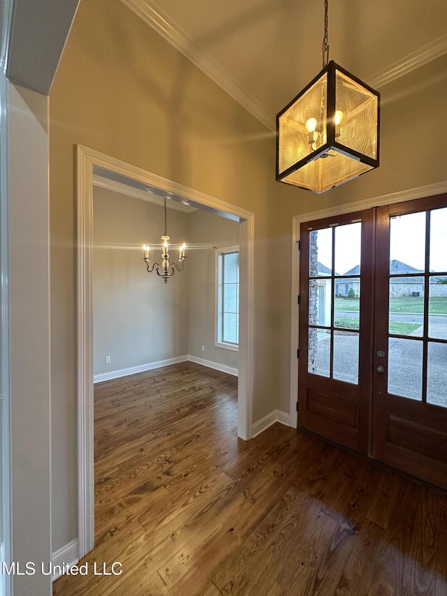foyer featuring dark wood-style flooring, a notable chandelier, french doors, baseboards, and ornamental molding