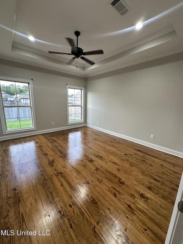 unfurnished room with visible vents, ornamental molding, a raised ceiling, and dark wood-type flooring