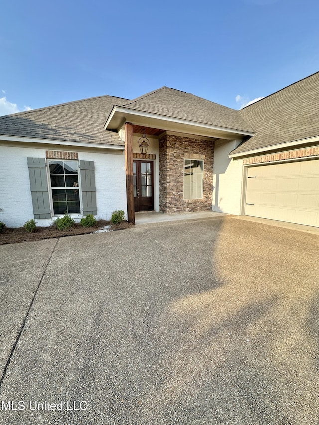 ranch-style house with roof with shingles, an attached garage, concrete driveway, and french doors