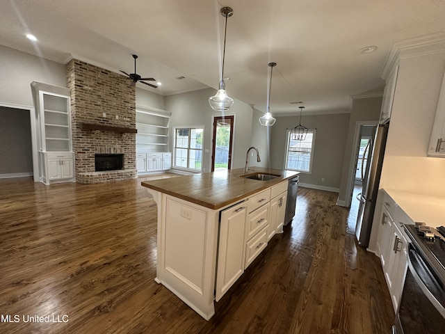 kitchen with ceiling fan, appliances with stainless steel finishes, a sink, a brick fireplace, and ornamental molding