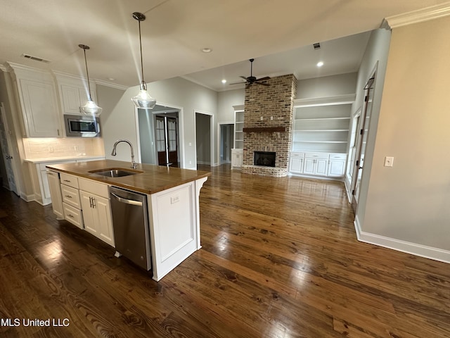 kitchen featuring dark countertops, ceiling fan, appliances with stainless steel finishes, a sink, and ornamental molding
