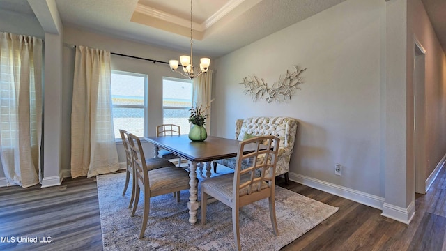 dining space with dark hardwood / wood-style floors, an inviting chandelier, a tray ceiling, and crown molding