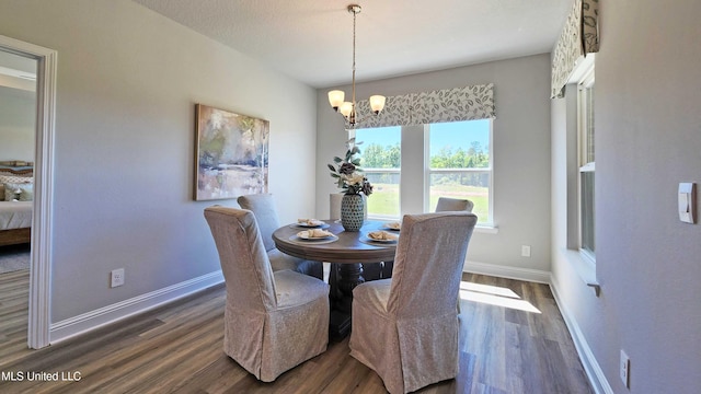 dining area featuring dark wood-type flooring, a textured ceiling, and a notable chandelier