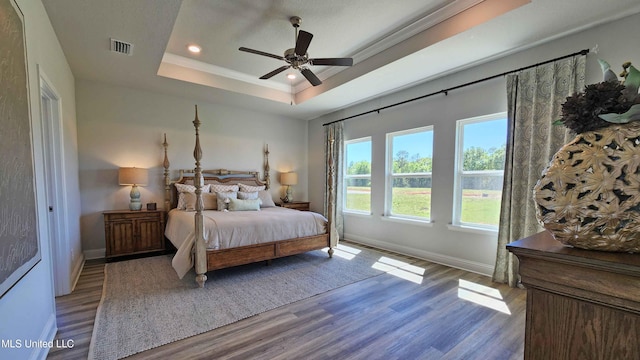 bedroom with a tray ceiling, ceiling fan, and light hardwood / wood-style floors