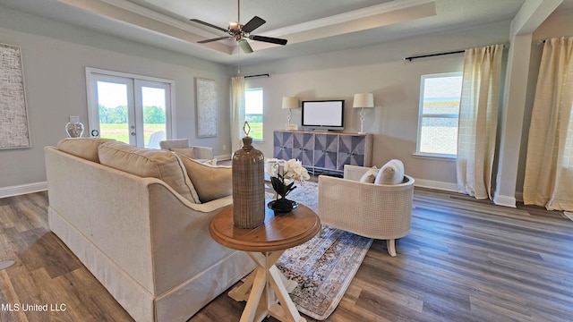 living room with ceiling fan, french doors, dark hardwood / wood-style flooring, a tray ceiling, and ornamental molding