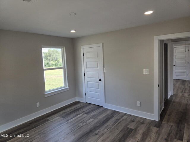 empty room featuring dark wood-style flooring, baseboards, and recessed lighting
