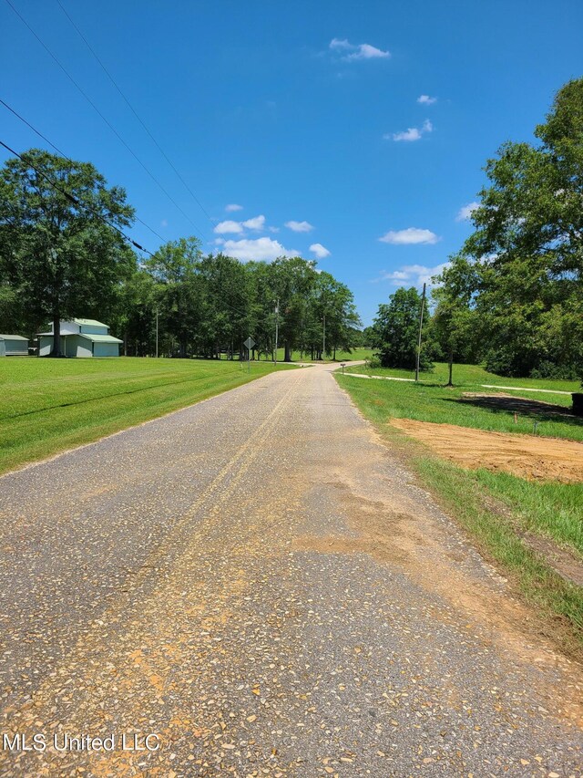 view of asphalt street with view of wooded area