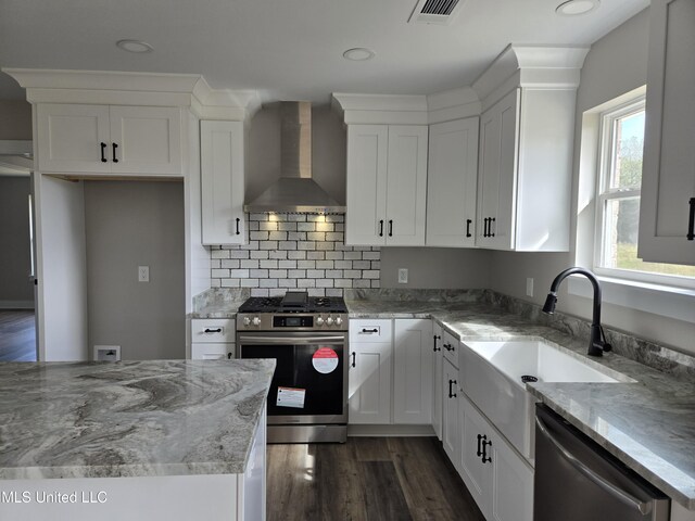 kitchen with appliances with stainless steel finishes, wall chimney exhaust hood, dark wood finished floors, white cabinetry, and recessed lighting