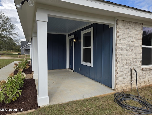 property entrance featuring board and batten siding, a porch, and brick siding