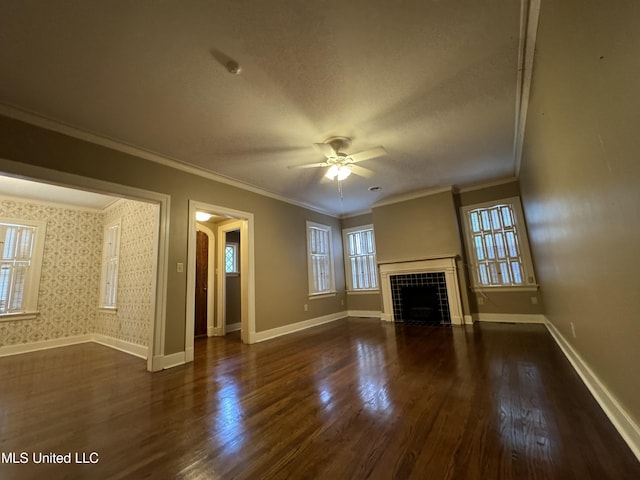 unfurnished living room featuring crown molding, dark wood-type flooring, a tile fireplace, and ceiling fan